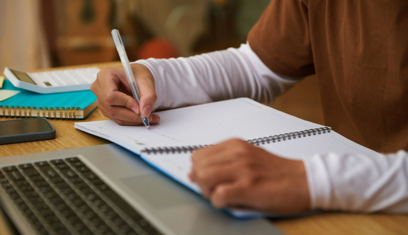 Man writing in notebook on desk