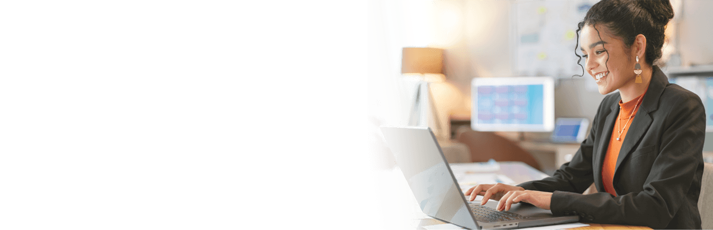 Young professional woman smiling as she types on a laptop
