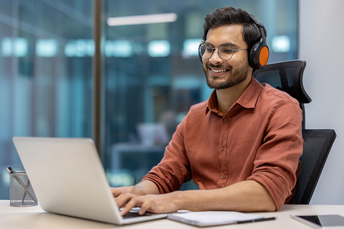 Young male using laptop and headphones in an office