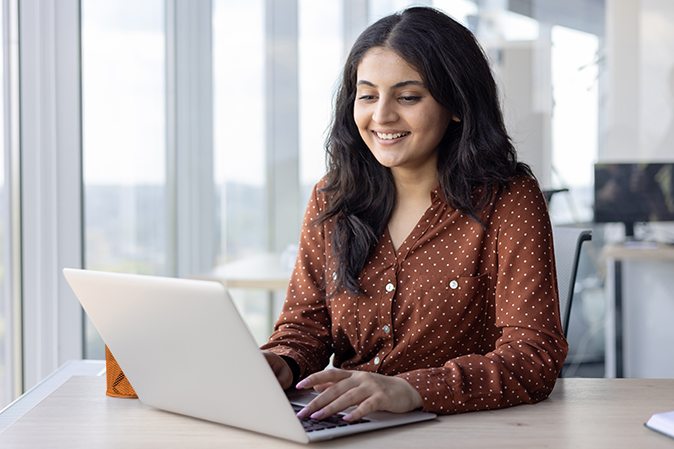 Young woman smiling while typing on laptop in office