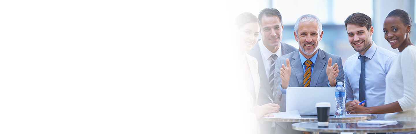 Group of men and women professionals smiling in front of a laptop on a high top table