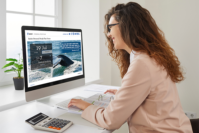 Woman smiling while working on her laptop with her personalized study plan