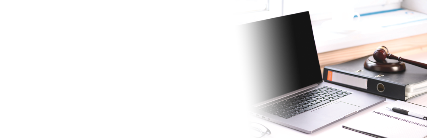 Laptop sitting on a desk with a notepad, binder and a judge's gavel