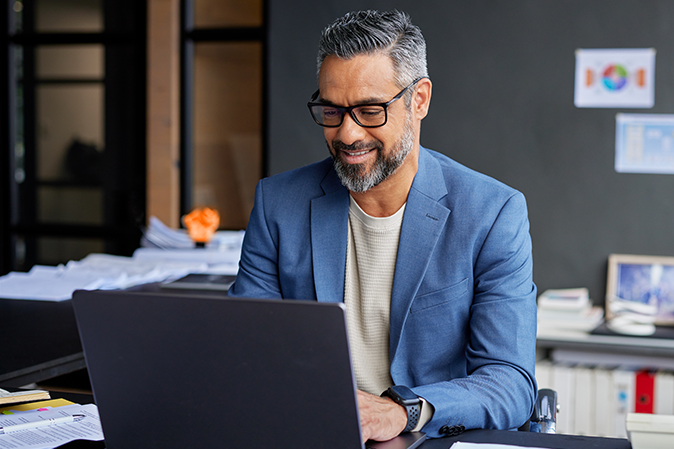Professional business man smiling and typing on laptop