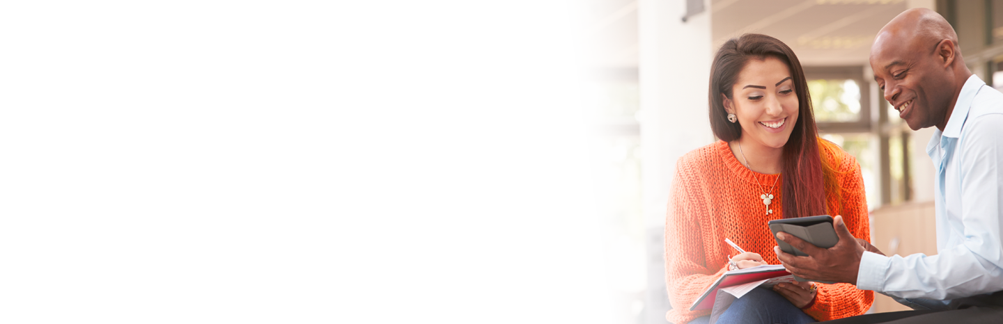 Older man holding a tablet working with a student who is taking notes