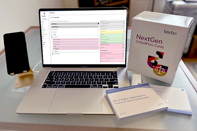 Desk with a mobile device, laptop choosing digital critical pass card with the actual set of NextGen cards sitting next to it