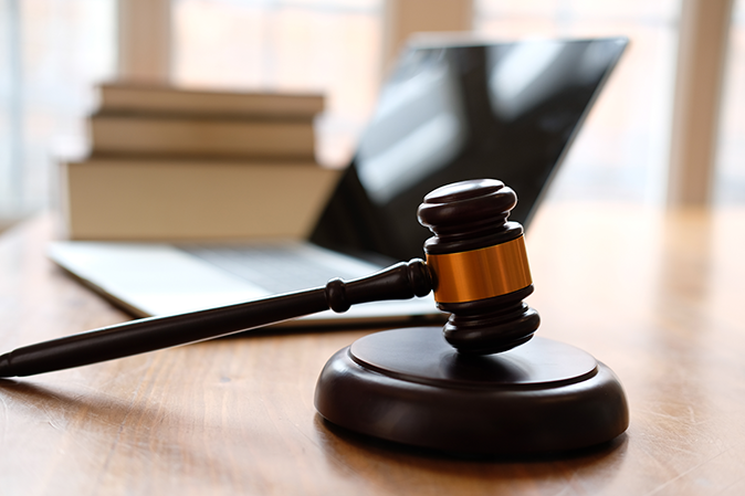 Judge's gavel sitting on a desk next to a laptop