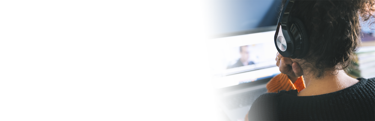 Woman wearing headphones while watching a video on laptop